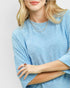 Person wearing a light blue sweater with a subtle pattern on a plain background