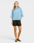 Woman wearing a light blue top and black shorts on a white background
