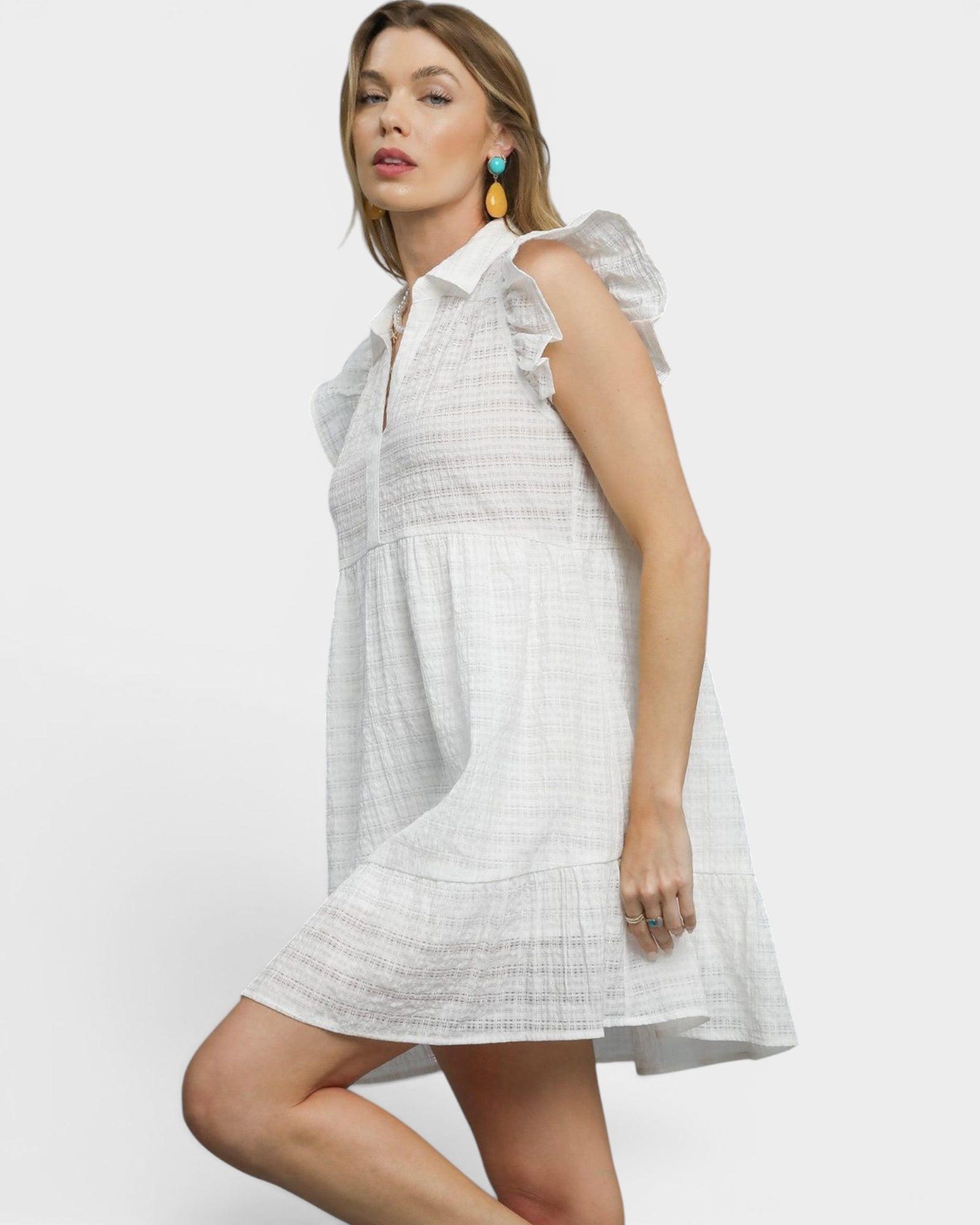 Woman wearing a white dress with ruffled sleeves on a plain background