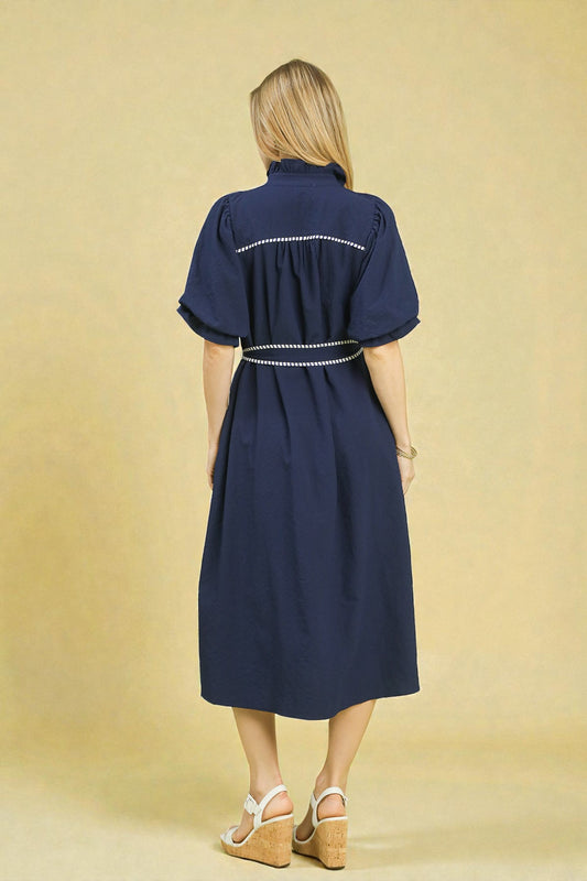 Woman wearing a navy dress with white trim on a beige background
