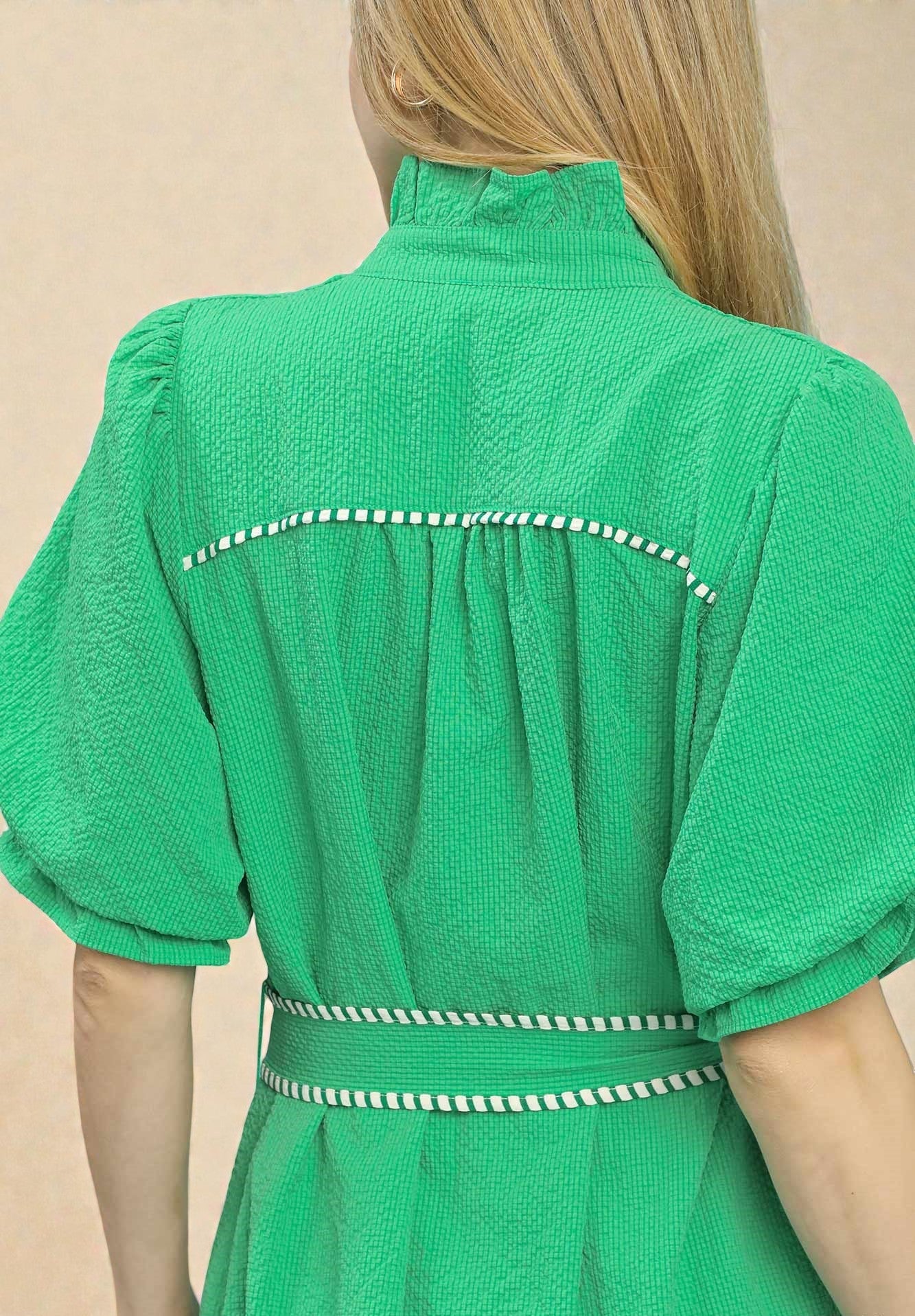 Green dress with white trim on a beige background