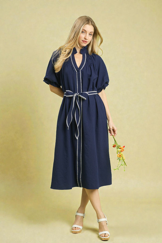 Woman wearing a navy dress with a belt on a beige background