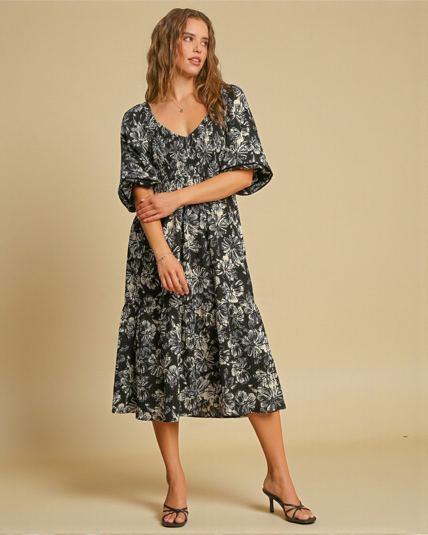 Woman wearing a black floral dress against a beige background