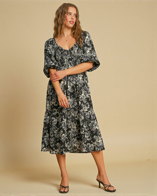 Woman wearing a black floral dress against a beige background