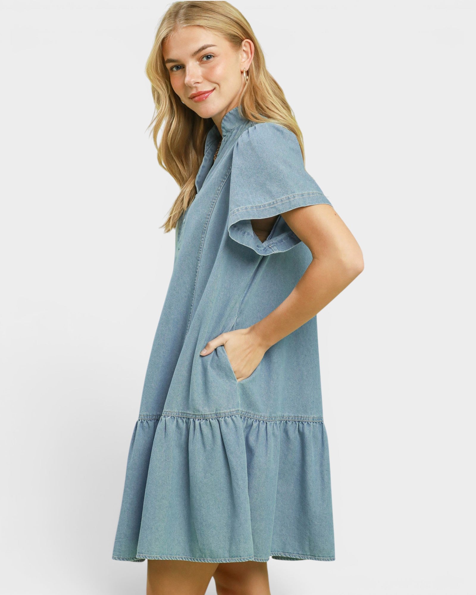 Woman wearing a light blue denim dress on a white background