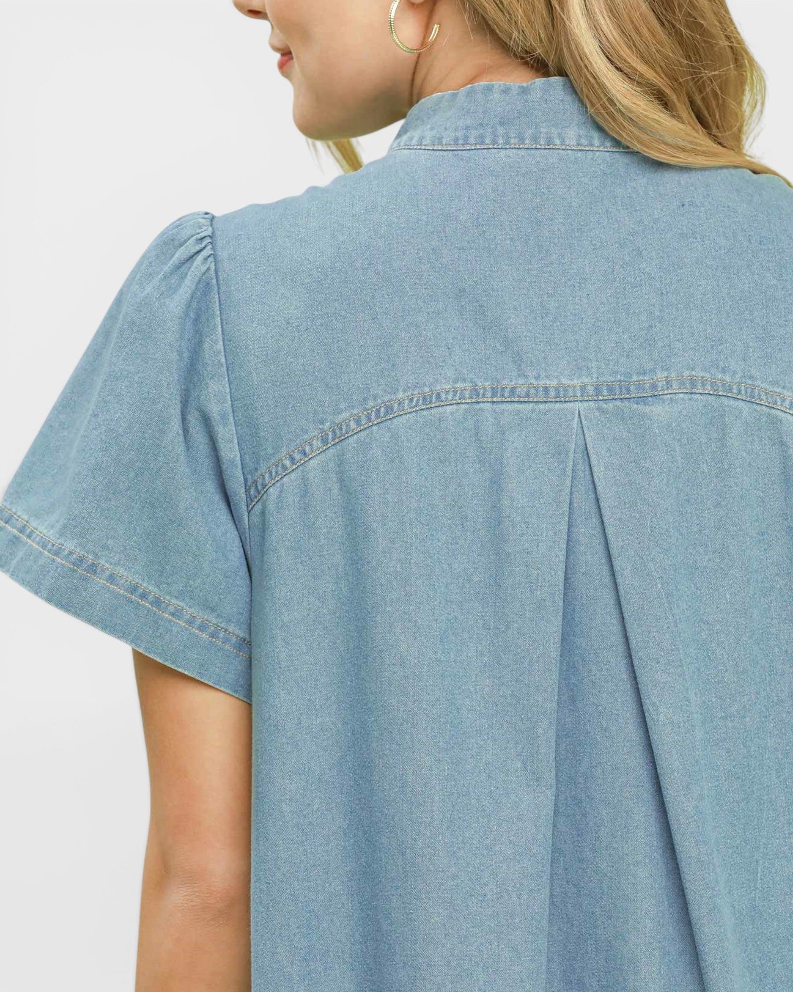 Light blue denim shirt worn by a person on a light gray background