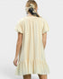 Woman wearing a light yellow dress with a plain white background