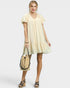 Woman wearing a light yellow dress holding a straw bag on a white background