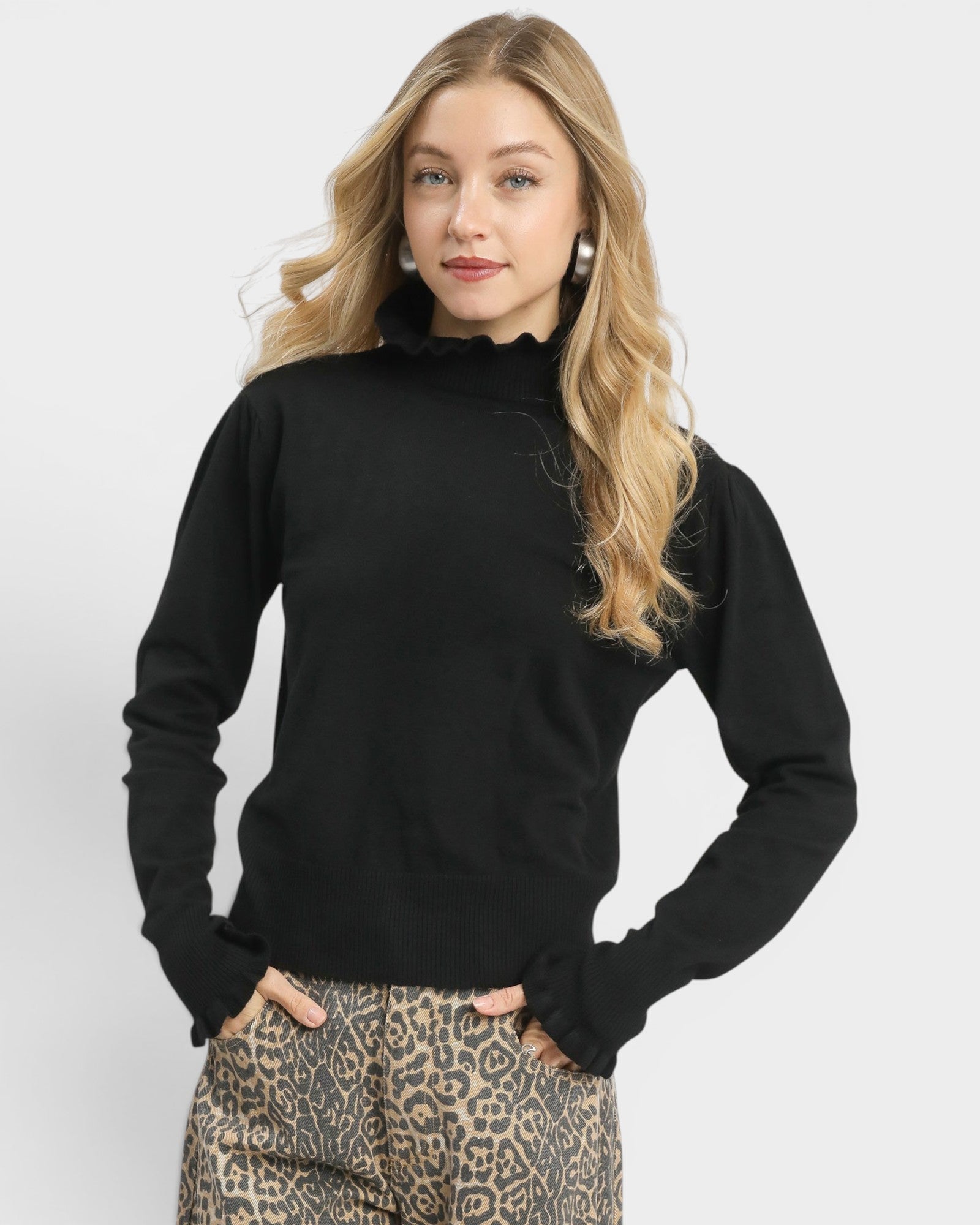 Woman wearing a black sweater and leopard print pants on a white background