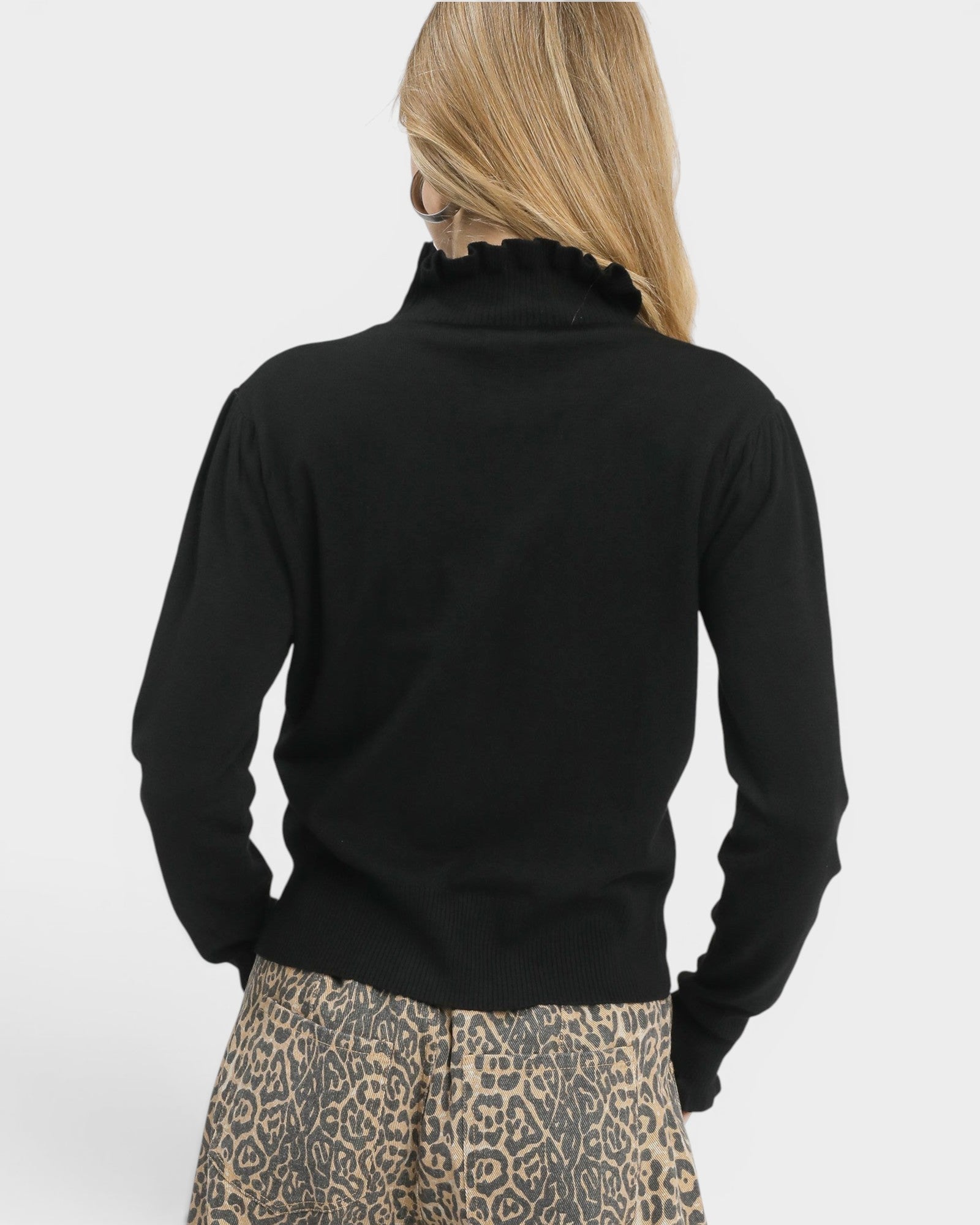 Person wearing a black long-sleeve top with a leopard print skirt on a white background