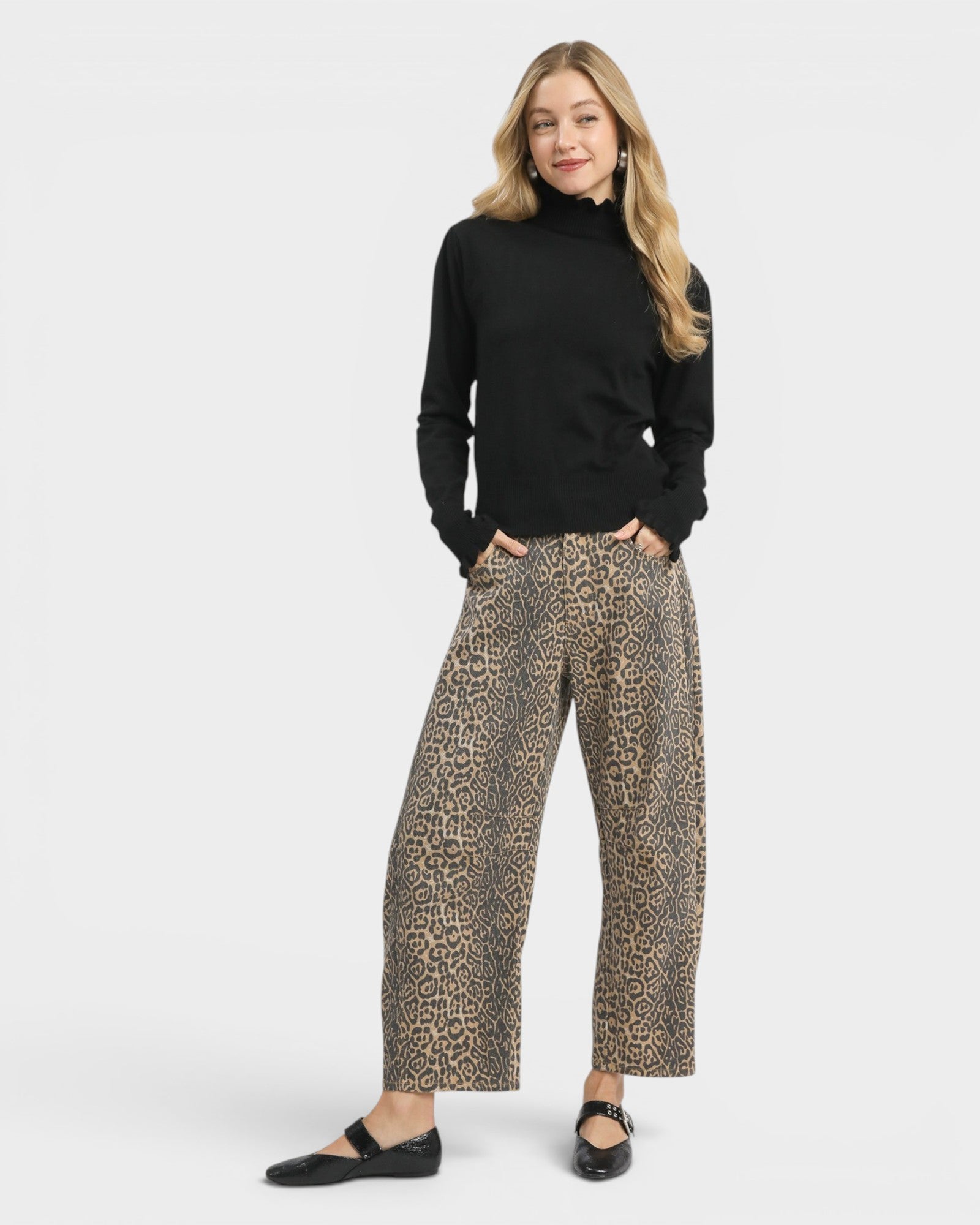 Woman wearing a black turtleneck and leopard print pants on a white background