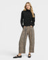 Woman wearing a black turtleneck and leopard print pants on a white background
