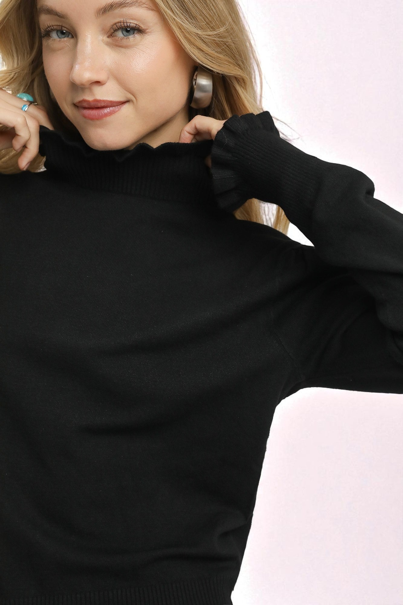 Woman wearing a black turtleneck sweater against a light pink background