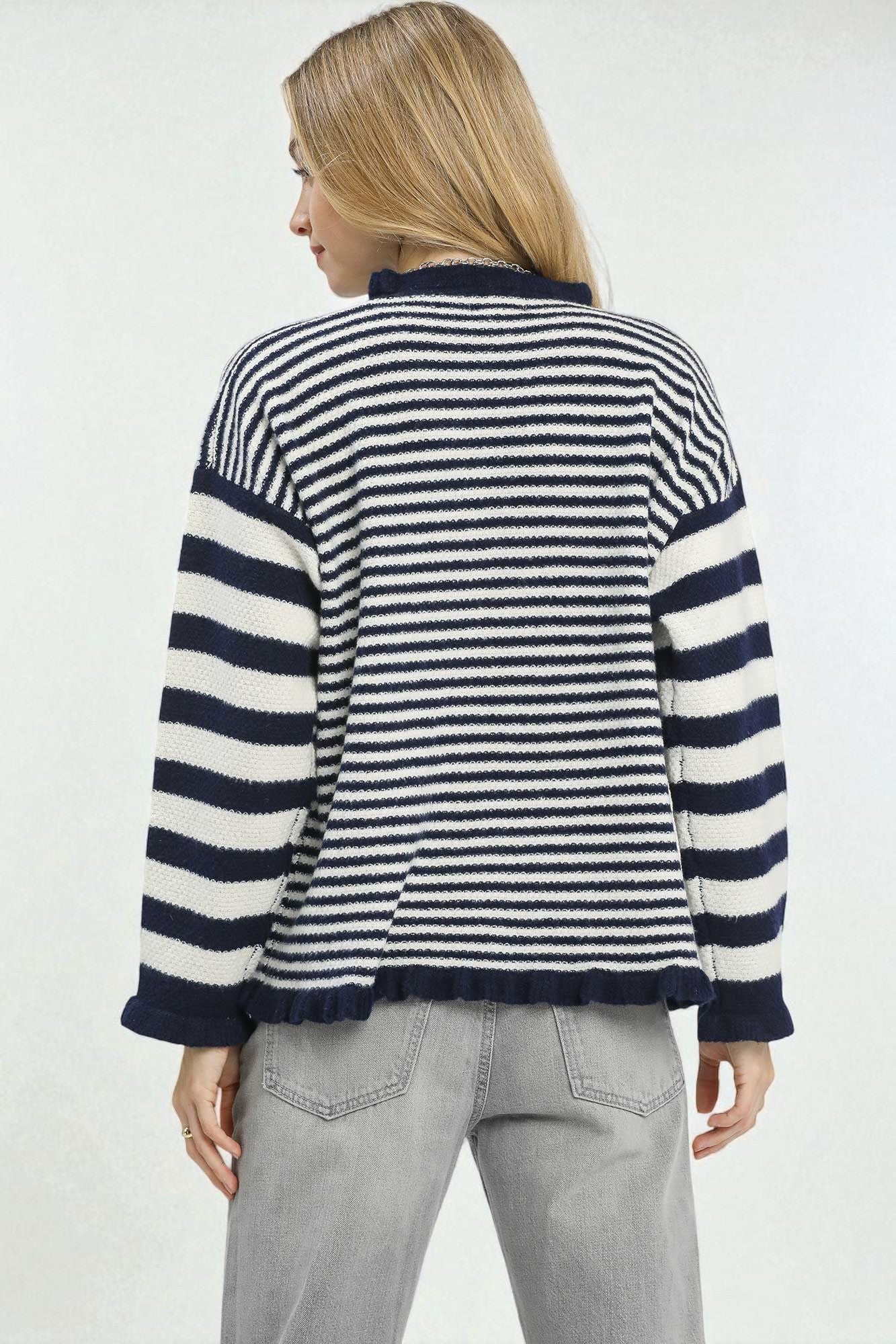 Woman wearing a navy and white striped sweater on a plain background