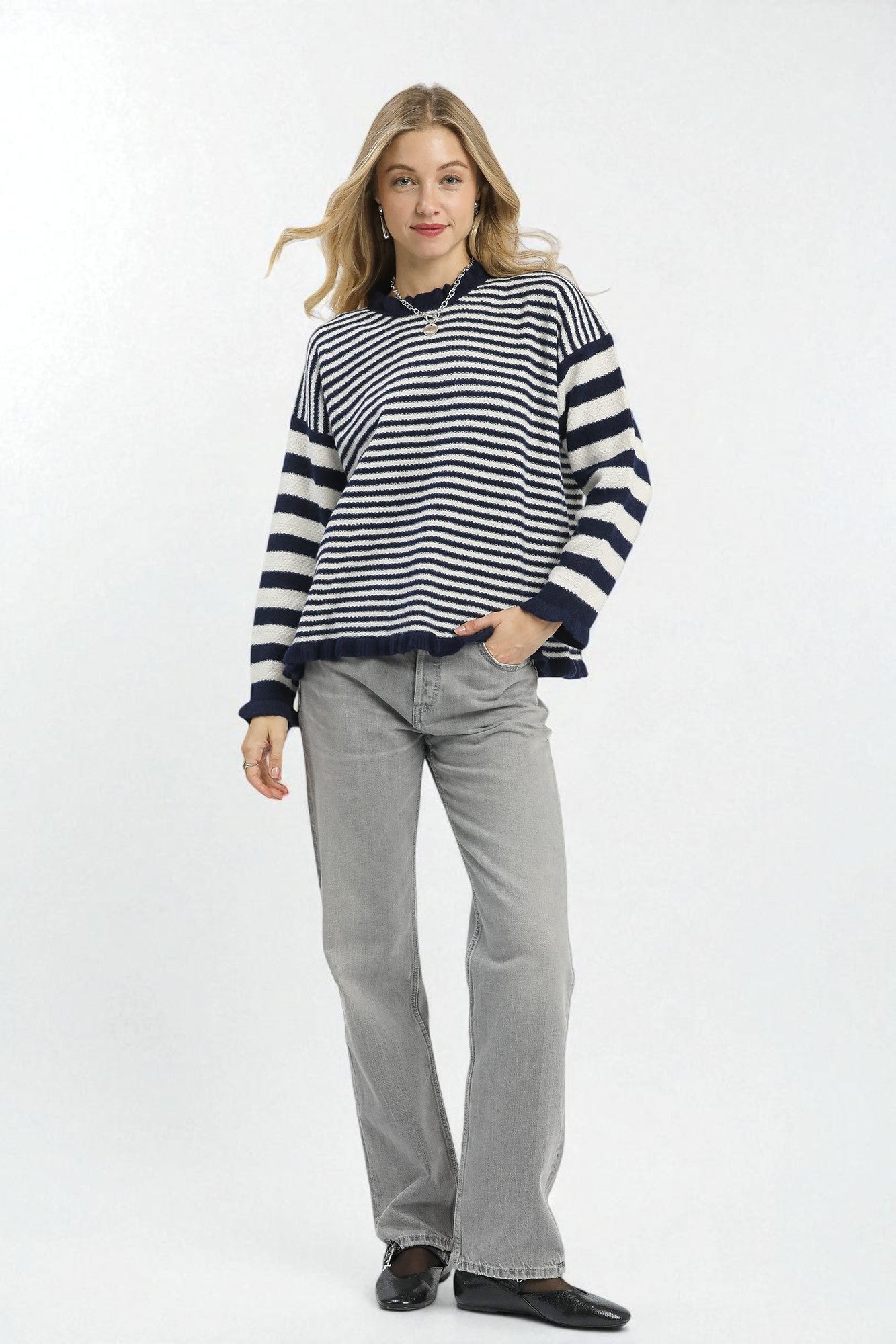 Woman wearing a black and white striped sweater and gray jeans on a white background