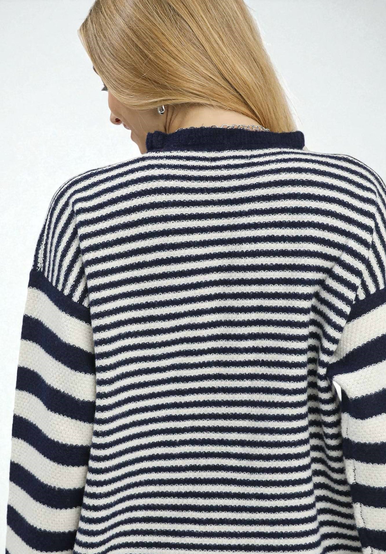 Person wearing a navy and white striped sweater with a blurred background