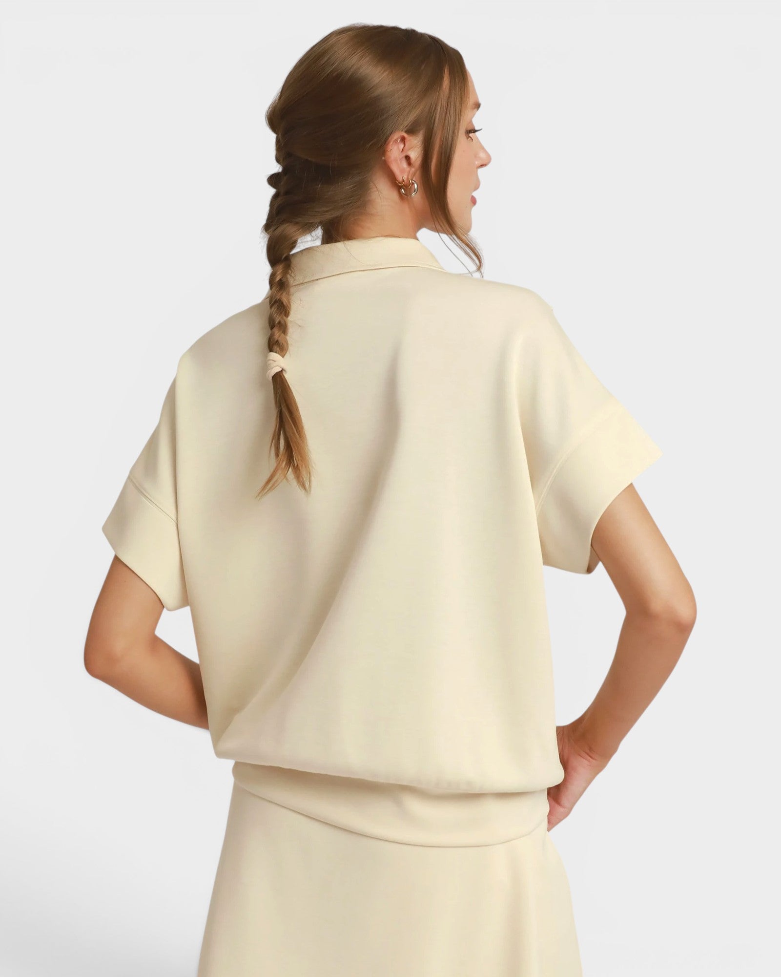 Woman wearing a beige outfit with a plain background