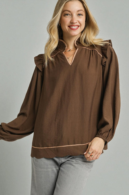 Woman wearing a brown blouse with a high collar against a gray background