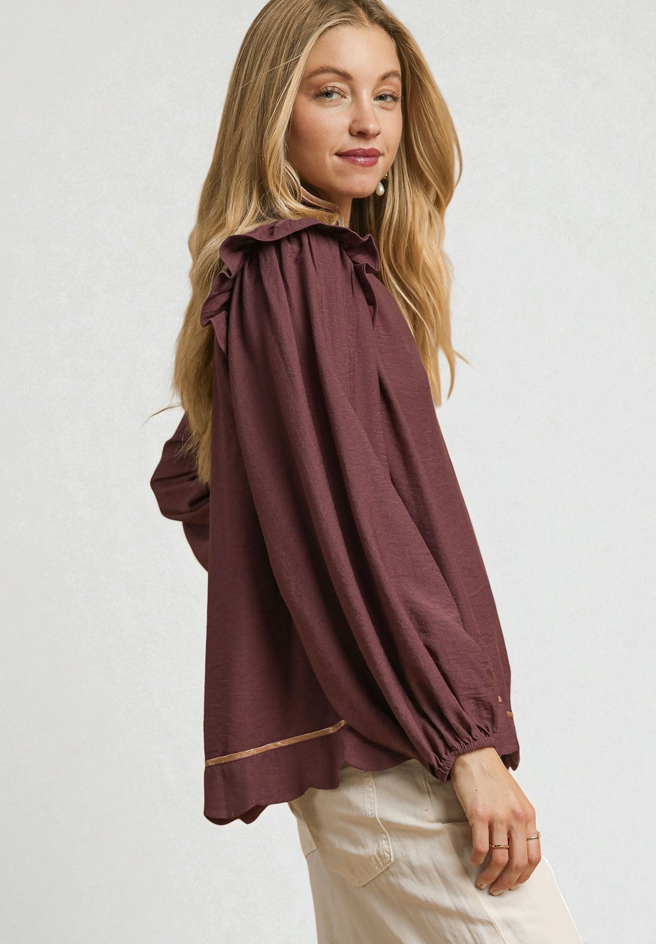 Woman wearing a burgundy blouse with a white background