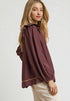 Woman wearing a burgundy blouse with a white background