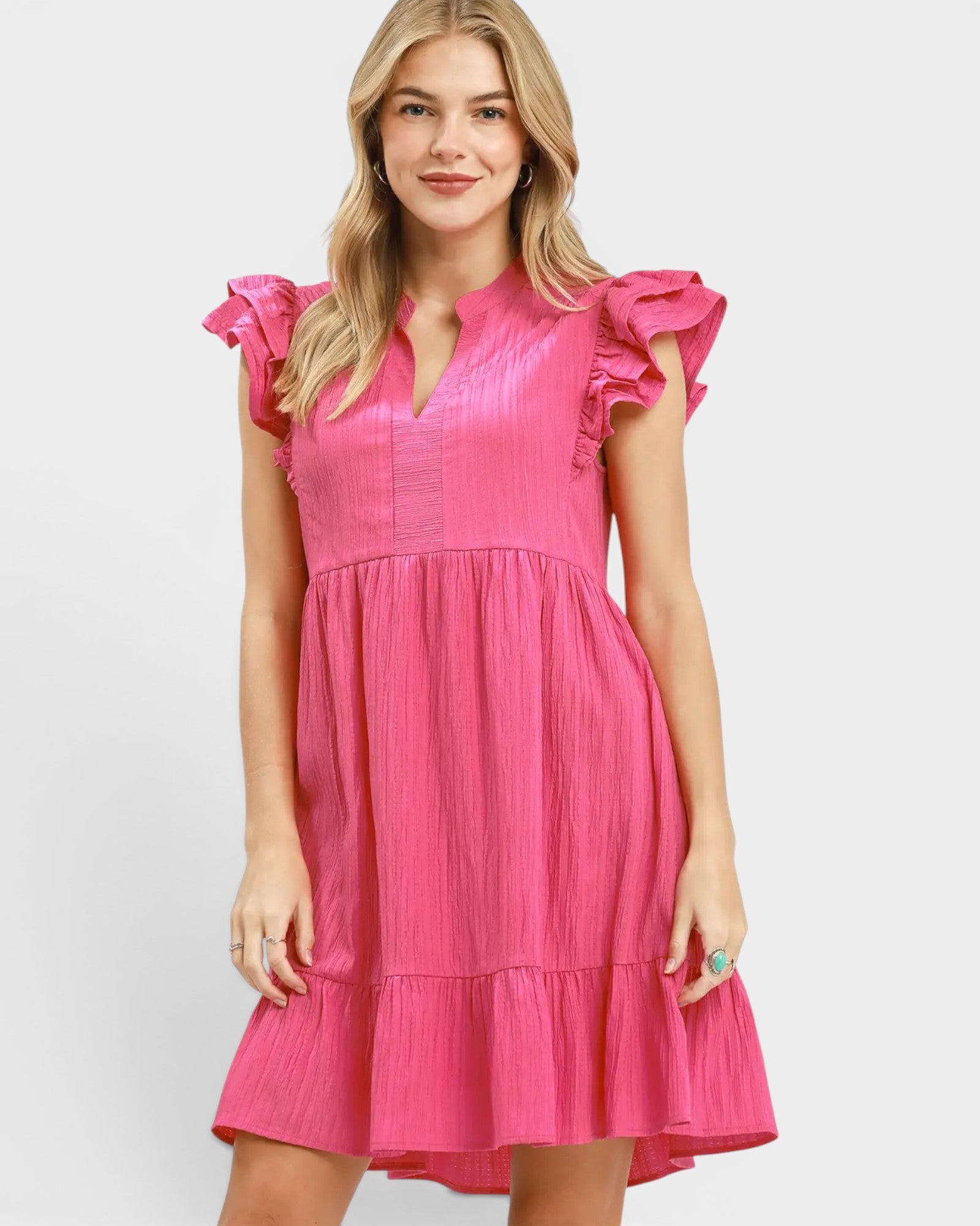 Woman wearing a pink dress with ruffled sleeves on a white background