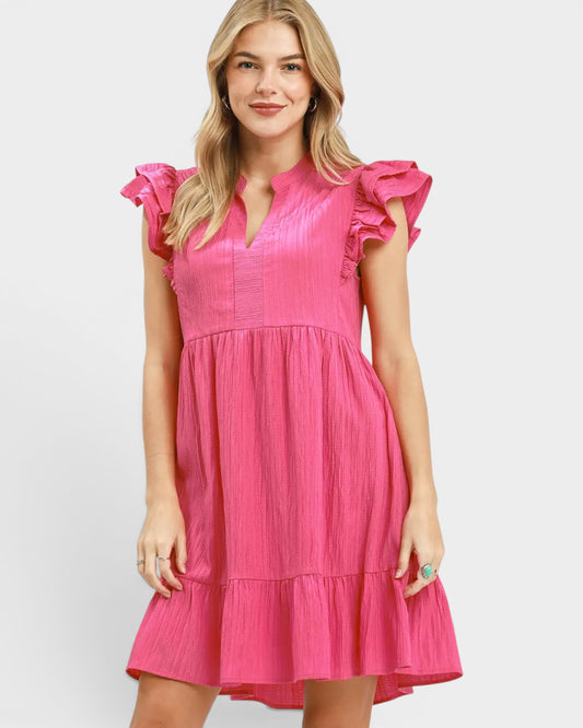 Woman wearing a pink dress with ruffled sleeves on a white background