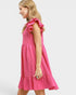 Woman wearing a pink dress with ruffled sleeves on a white background