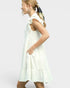 Woman wearing a white dress with ruffled sleeves on a plain background