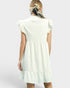 Woman wearing a white dress with ruffled sleeves on a plain background