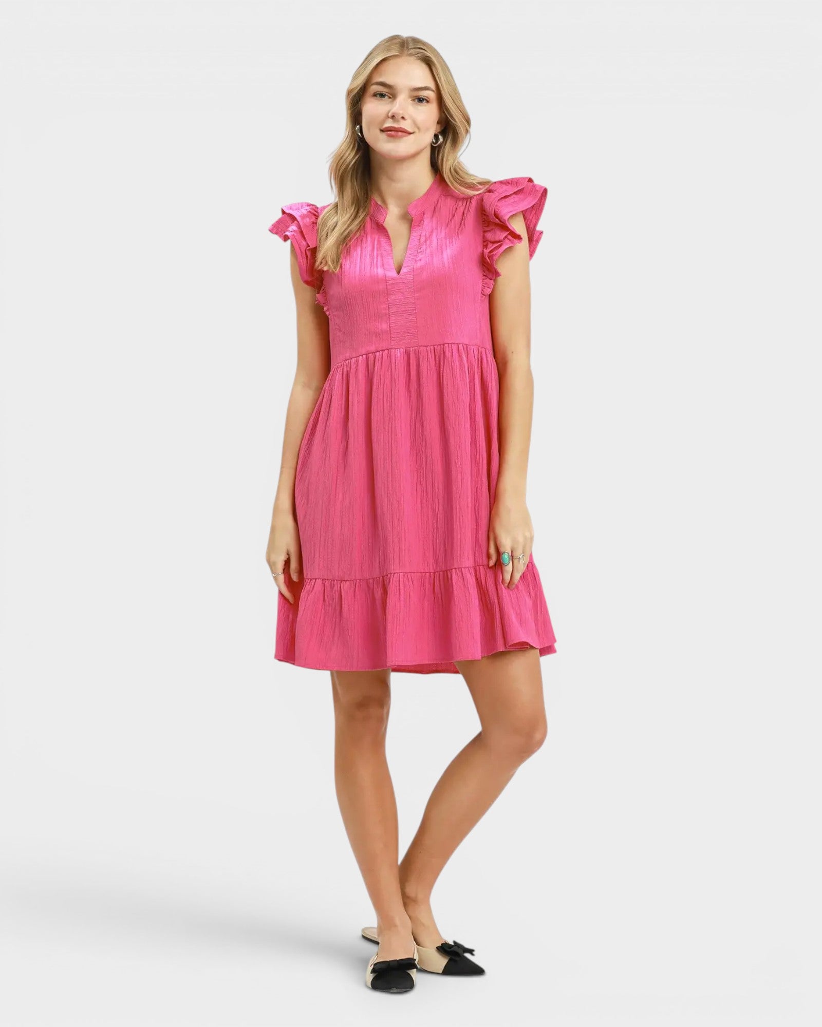 Woman wearing a pink dress with ruffled sleeves on a white background