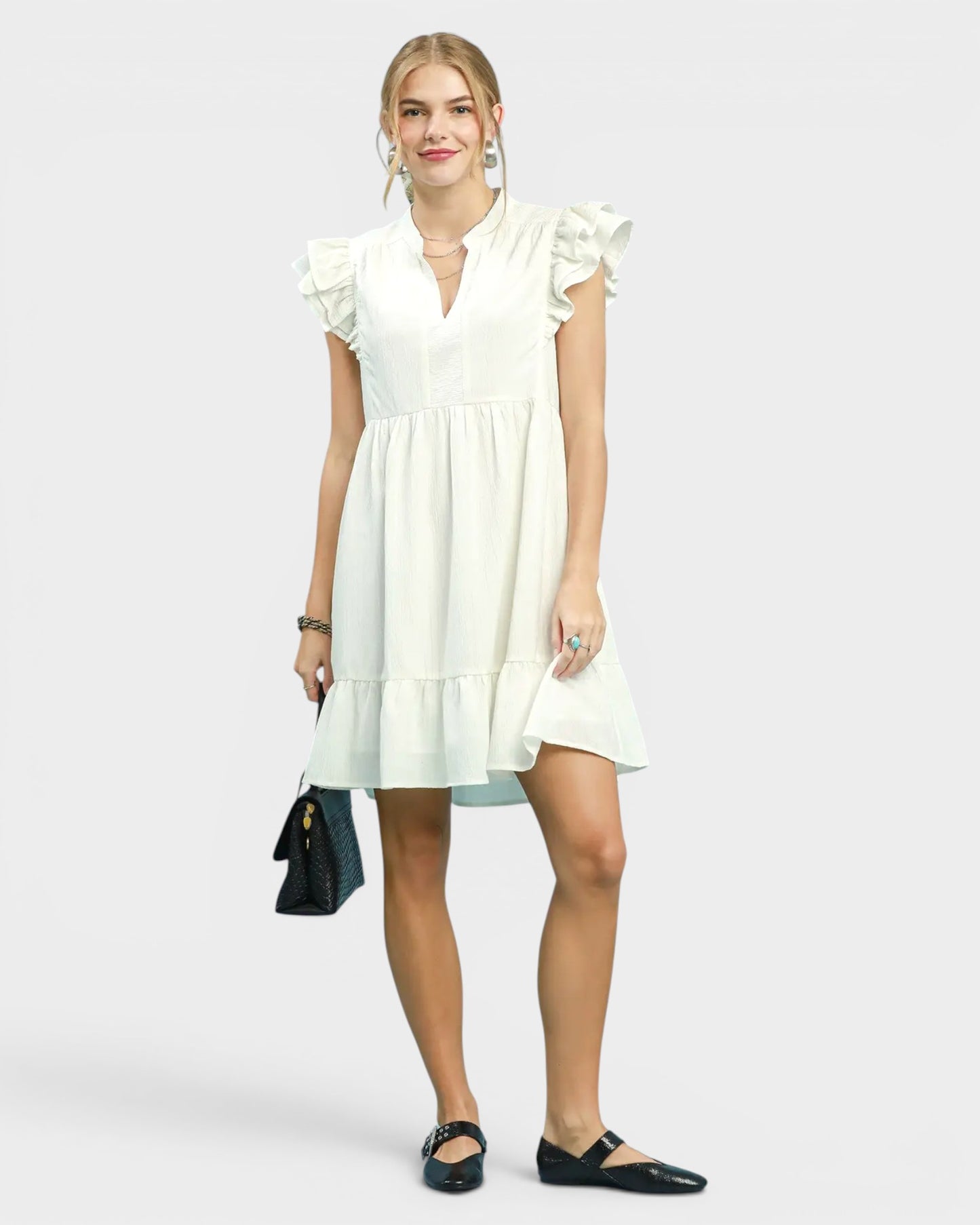 Woman wearing a white dress with ruffled sleeves on a plain background