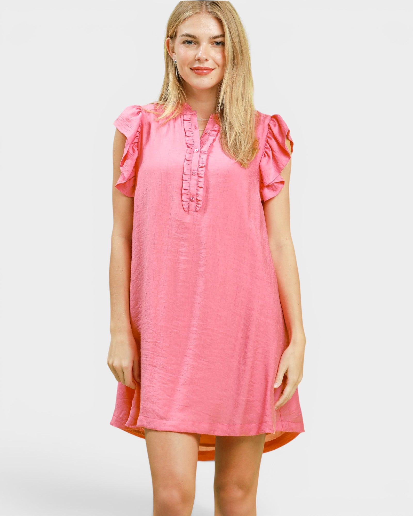 Woman wearing a pink dress with ruffled sleeves on a white background