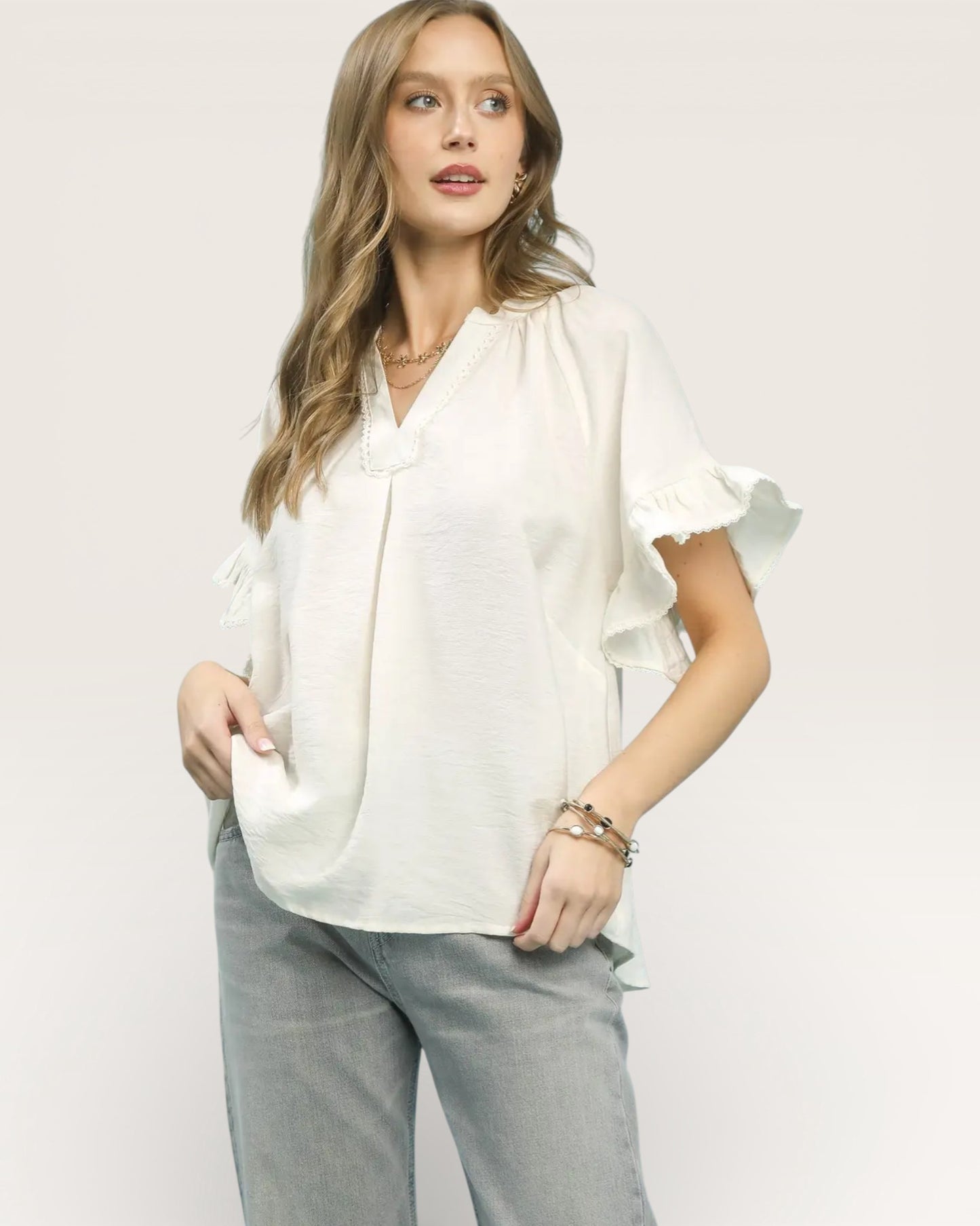 Woman wearing a white blouse with ruffled sleeves on a plain background