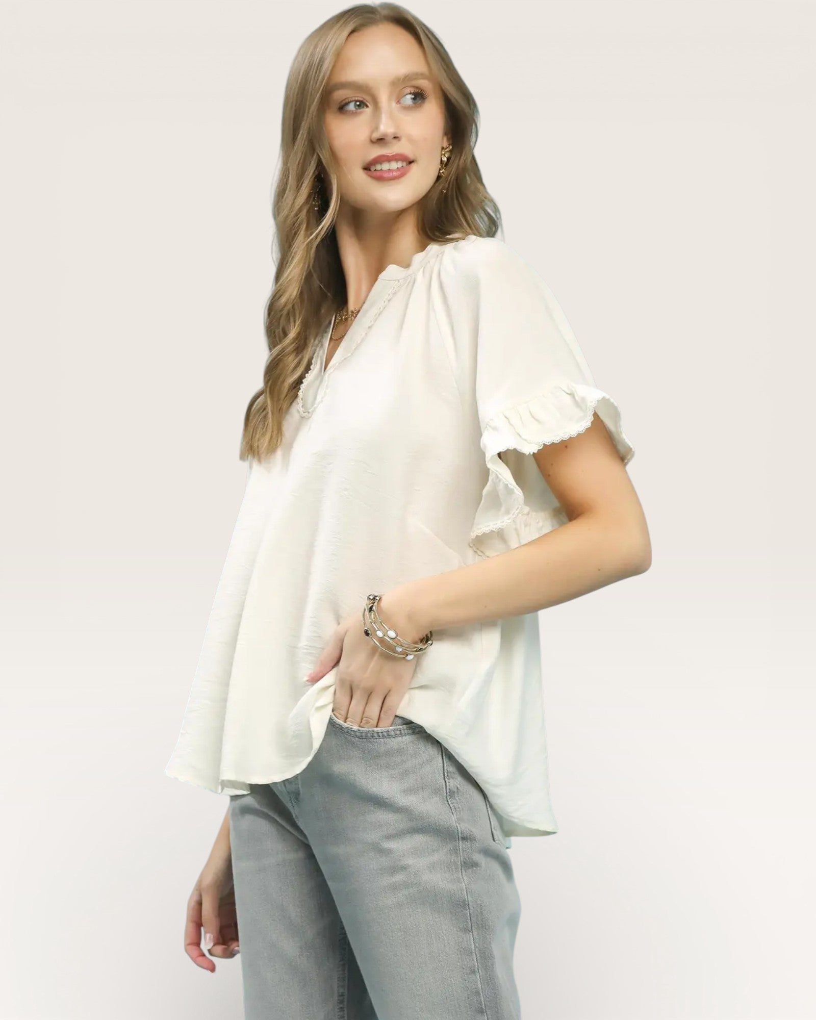 Woman wearing a white blouse with ruffled sleeves on a plain background