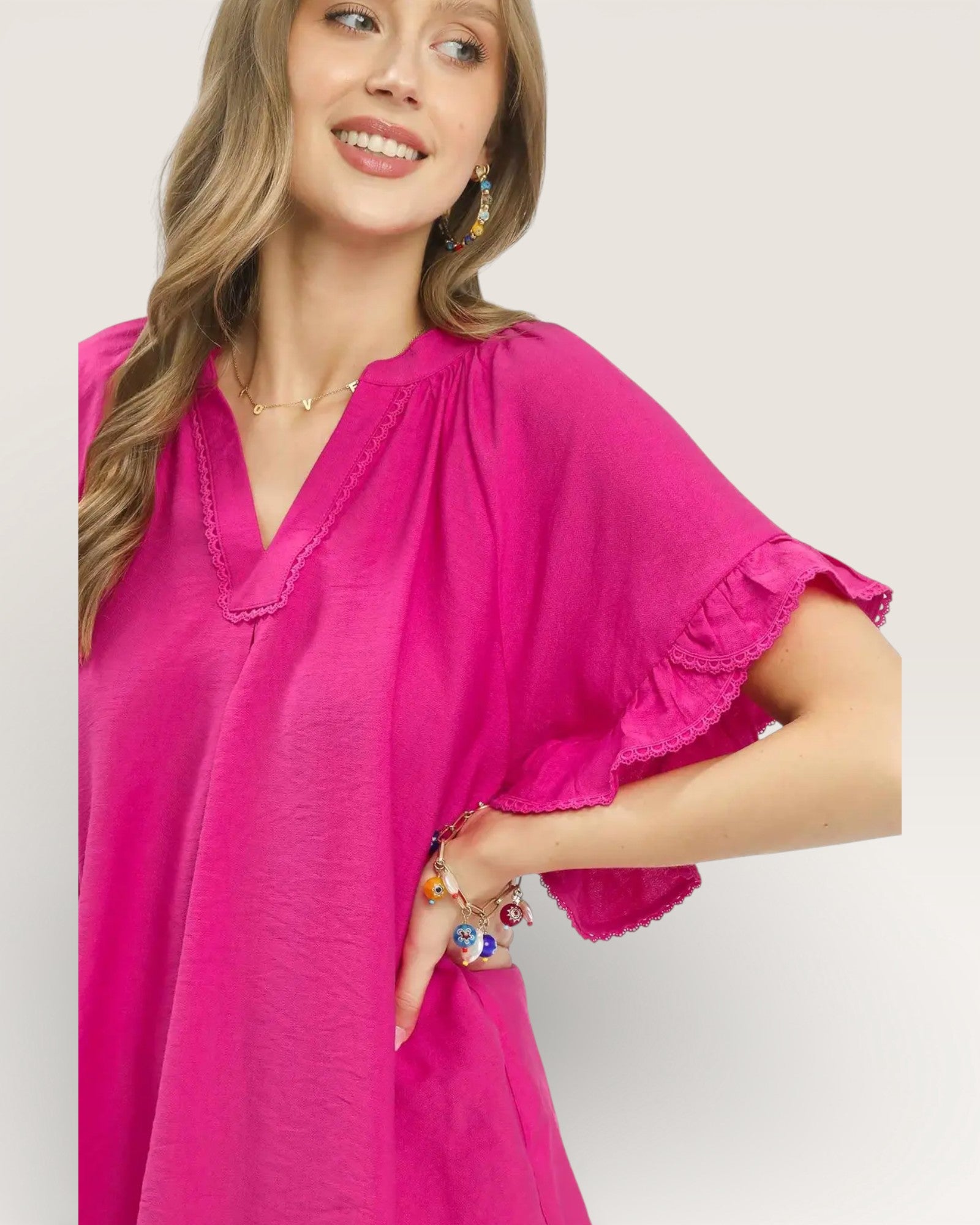 Woman wearing a bright pink dress with ruffled sleeves on a light background