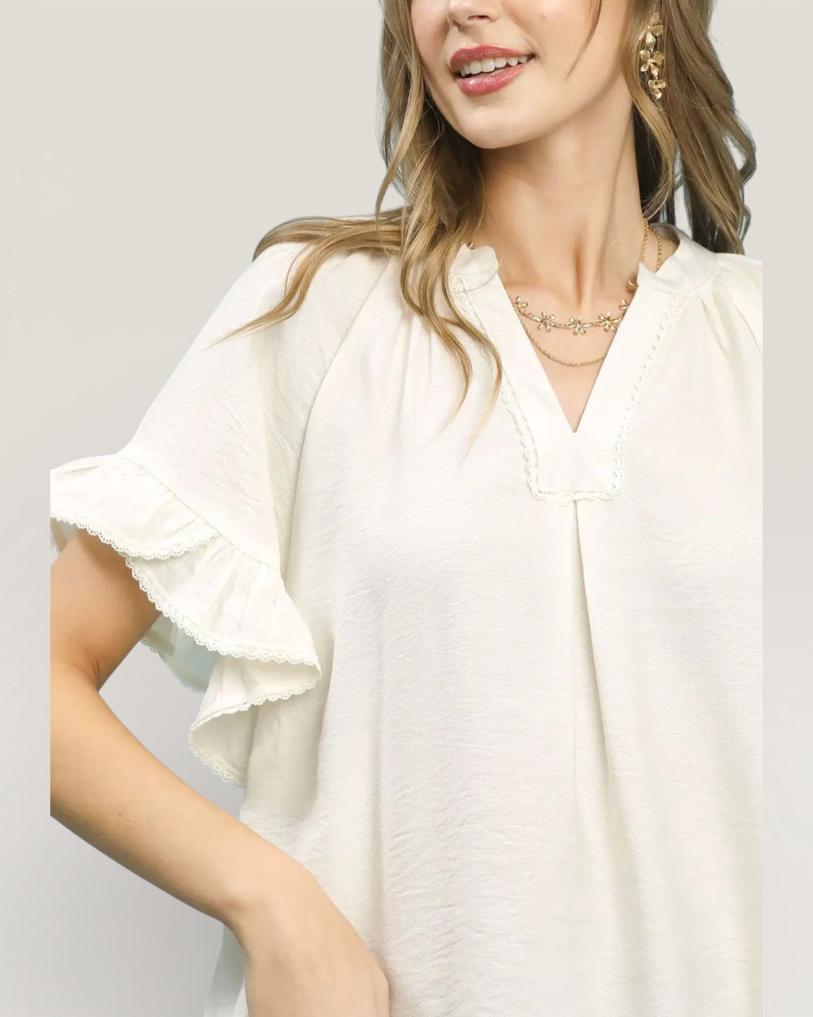 Woman wearing a white blouse with ruffled sleeves on a plain background
