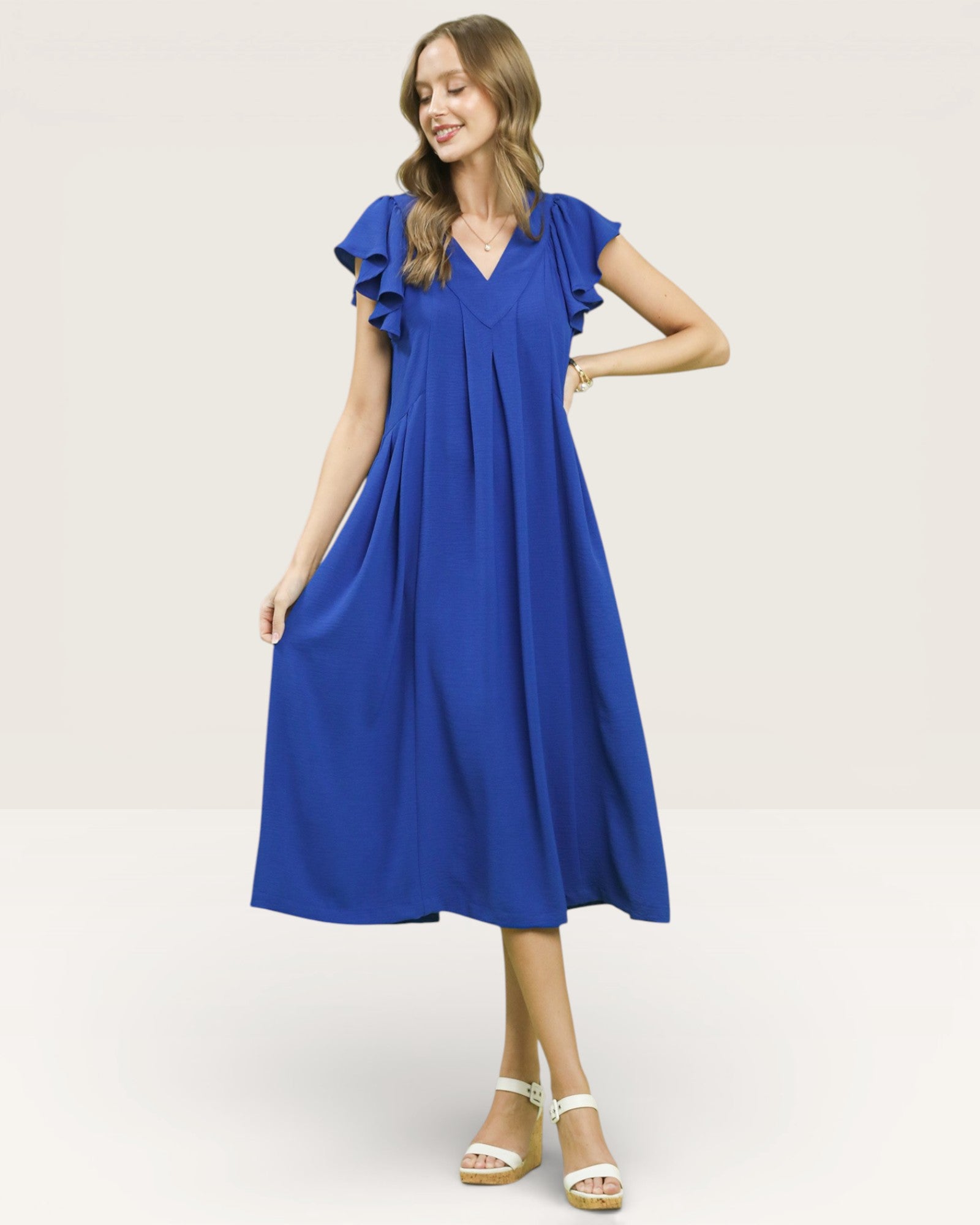 Woman wearing a blue dress with ruffled sleeves on a white background