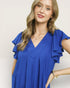 Woman wearing a blue blouse with ruffled sleeves against a plain background