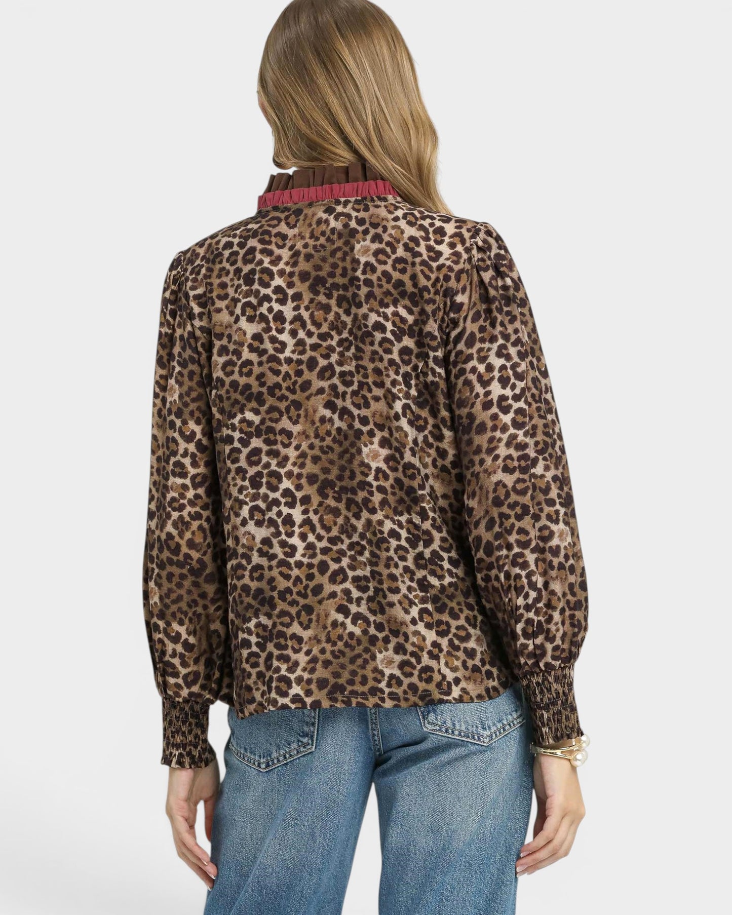 Person wearing a leopard print blouse and blue jeans on a white background