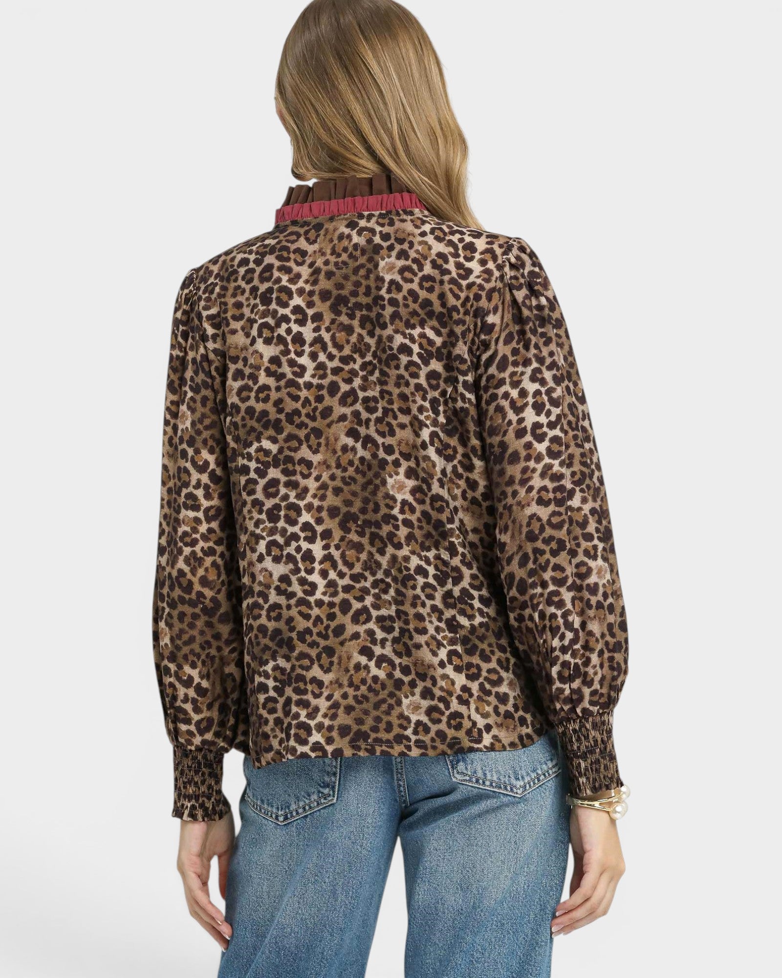 Person wearing a leopard print blouse and blue jeans on a white background