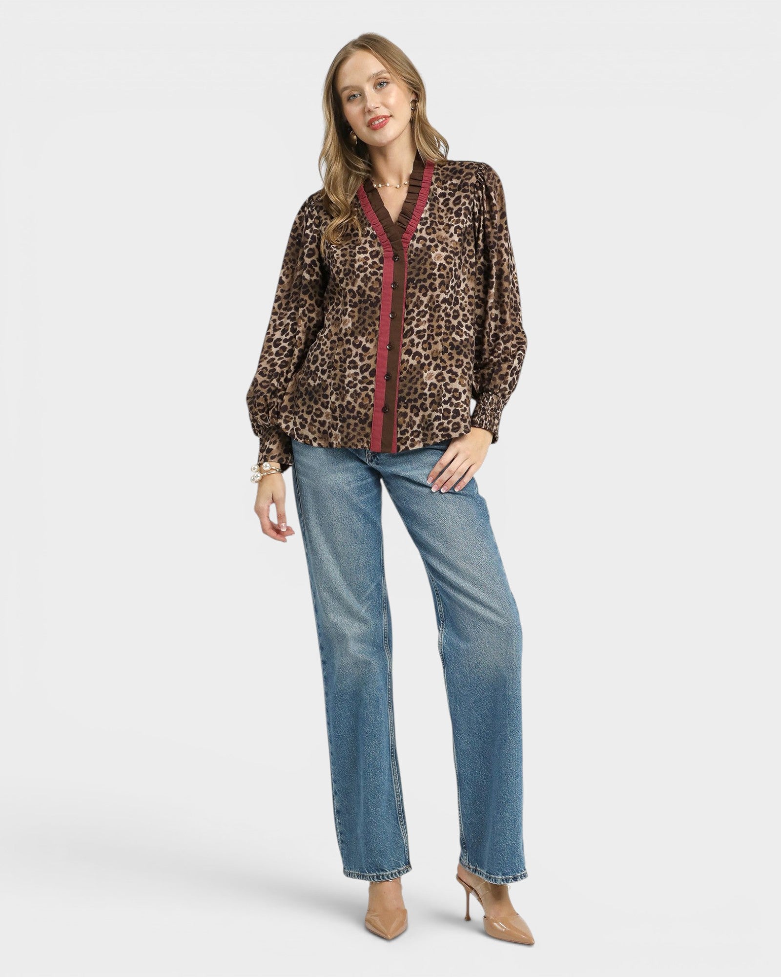Woman wearing a leopard print blouse with red trim and blue jeans on a white background