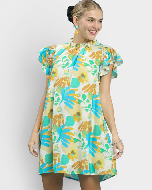 Woman wearing a colorful floral dress against a plain background