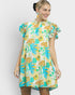 Woman wearing a colorful floral dress against a plain background