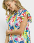 Woman wearing a colorful floral dress against a white background