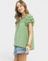 Woman wearing a green ruffled blouse and denim shorts on a white background