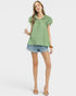 Woman wearing a green blouse and denim shorts on a white background