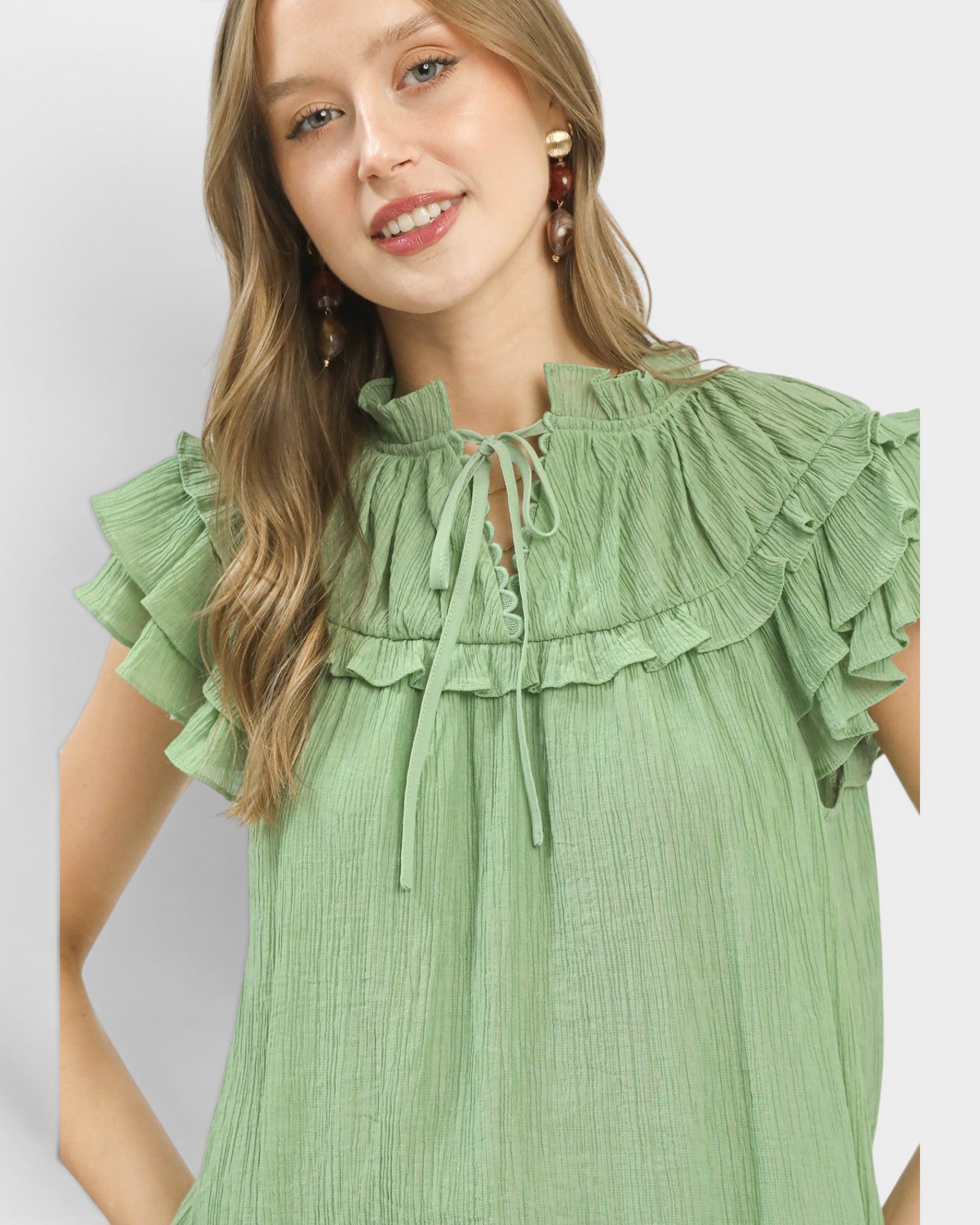Woman wearing a green dress with ruffled details on a plain background
