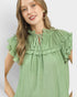 Woman wearing a green dress with ruffled details on a plain background