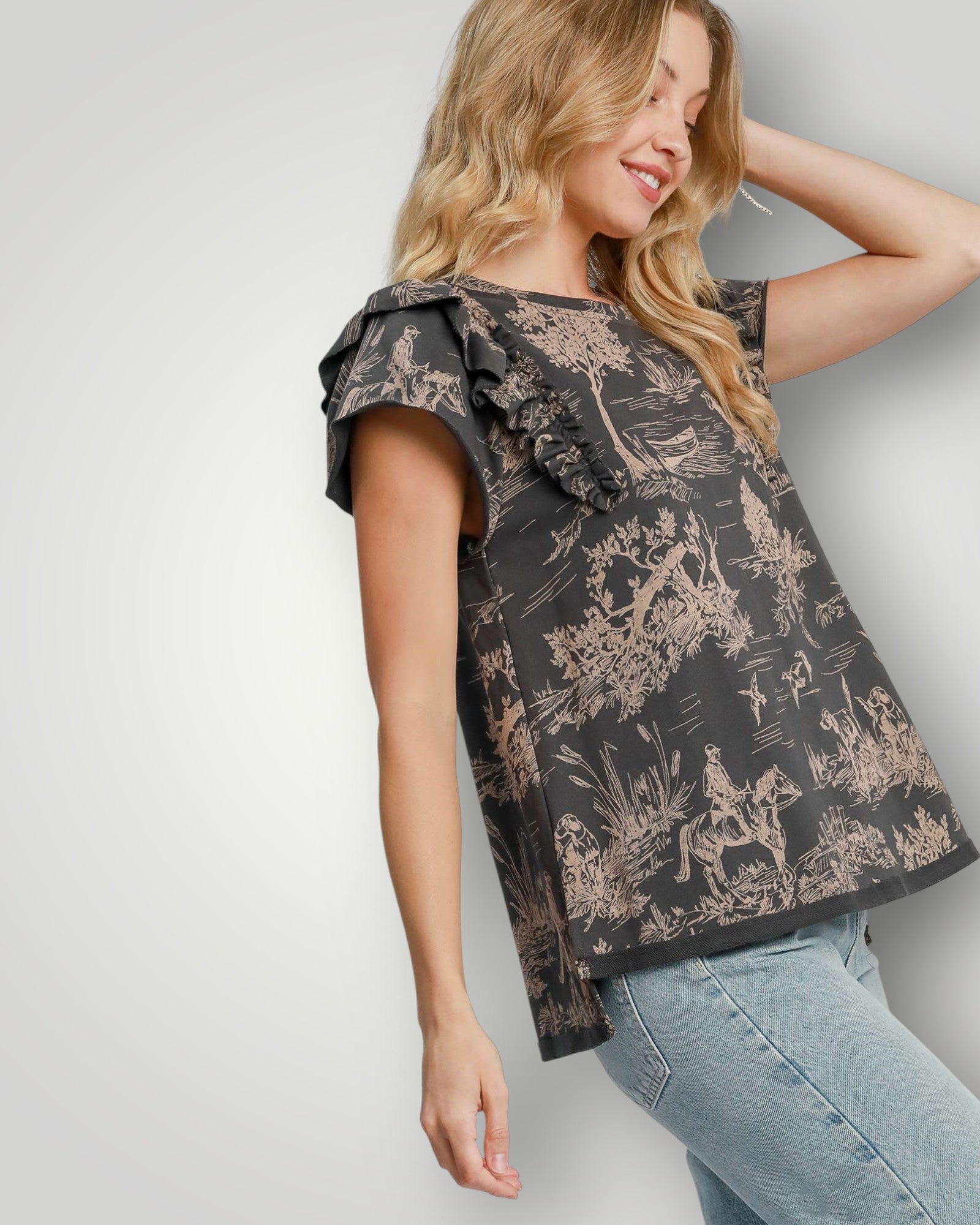 Woman wearing a black floral patterned top with ruffled sleeves against a white background