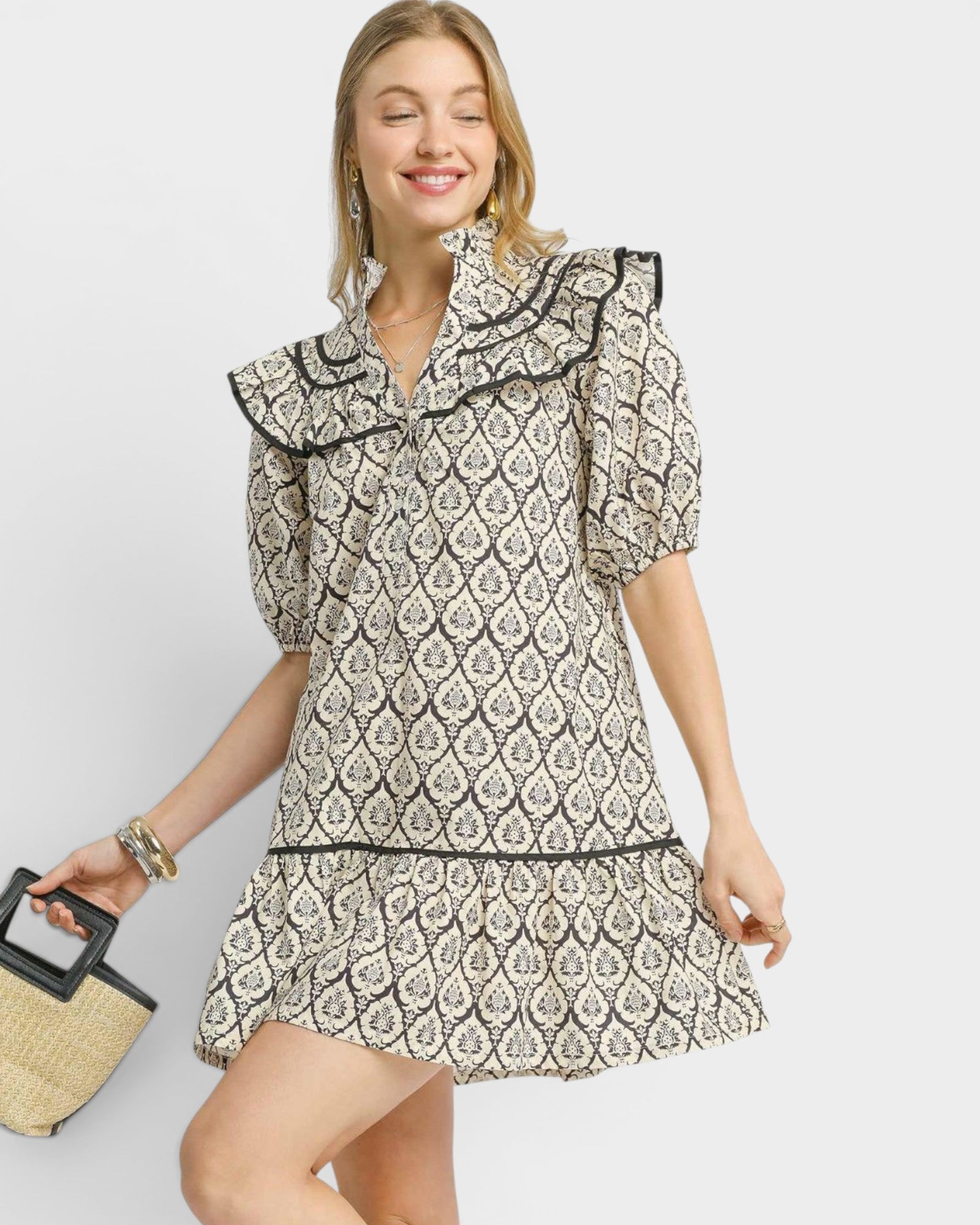 Woman wearing a patterned dress with ruffled collar on a plain background